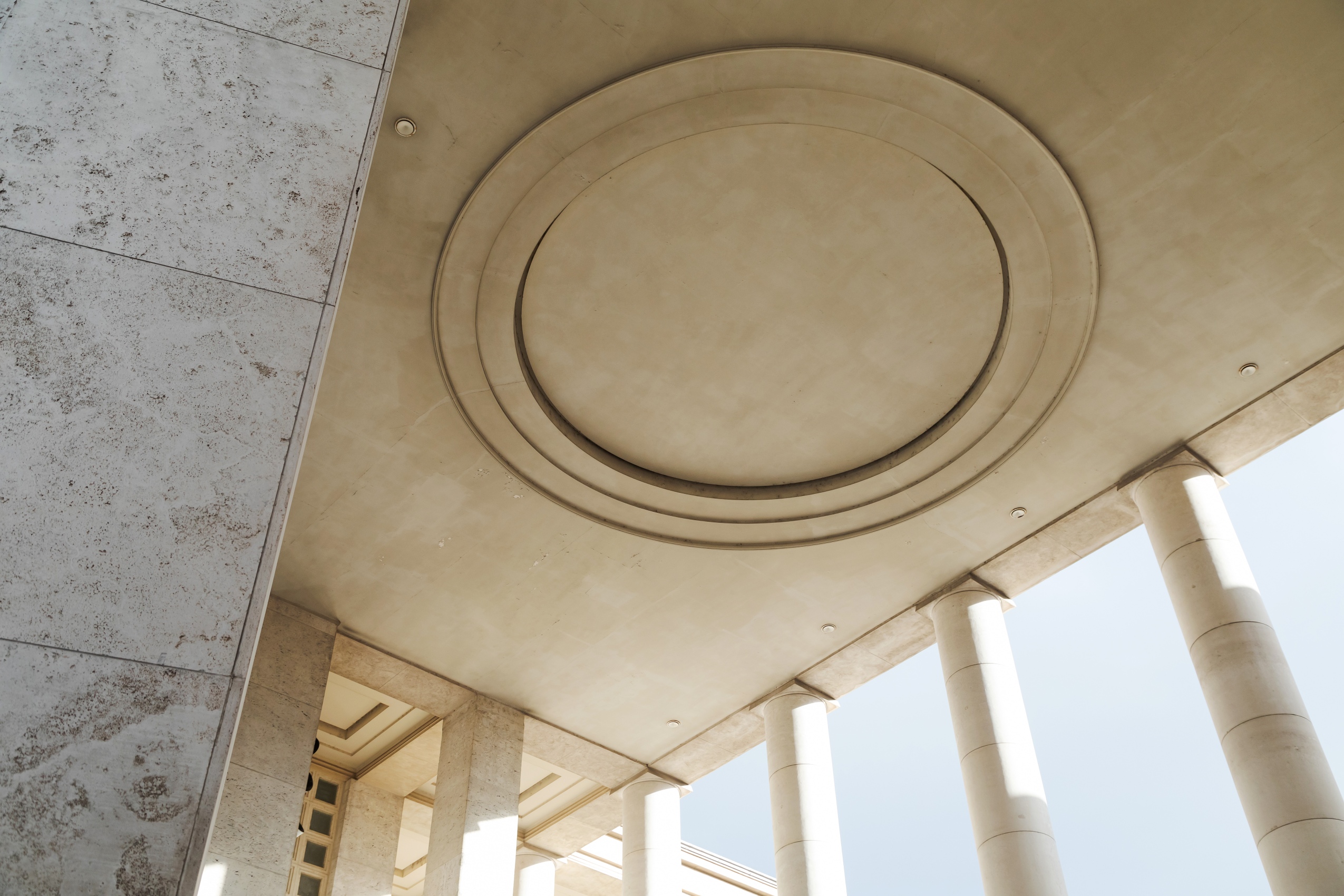 Entre les colonnes rondes et rectangulaires, le plafond de pierre aux reflets jaunes porte un bas relief circulaire, dont il est difficile de deviner la raison d’être.