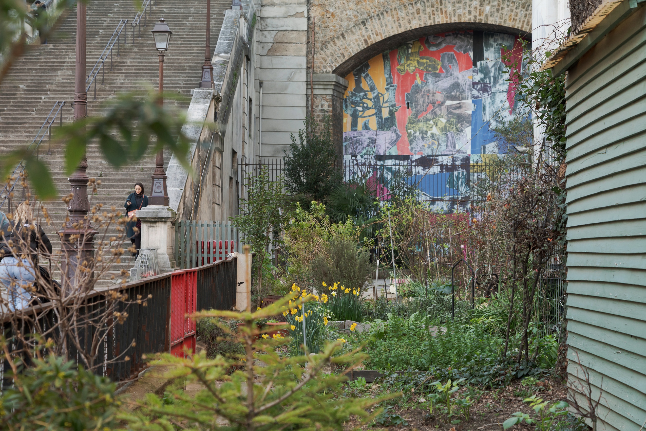 Les petites parcelles qui constituent le jardin aux habitants sont entourées de clôtures métalliques et sont parsemées de petites cabanes de jardin. Au fond de la rue, les escaliers remontent vers l’avenue, et une fresque géante aux couleurs vives marque l’entrée du jardin sauvage.